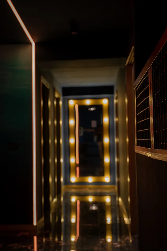 The entrance corridor, with a mirror framed by gold bulbs at the end and a glossy marble floor